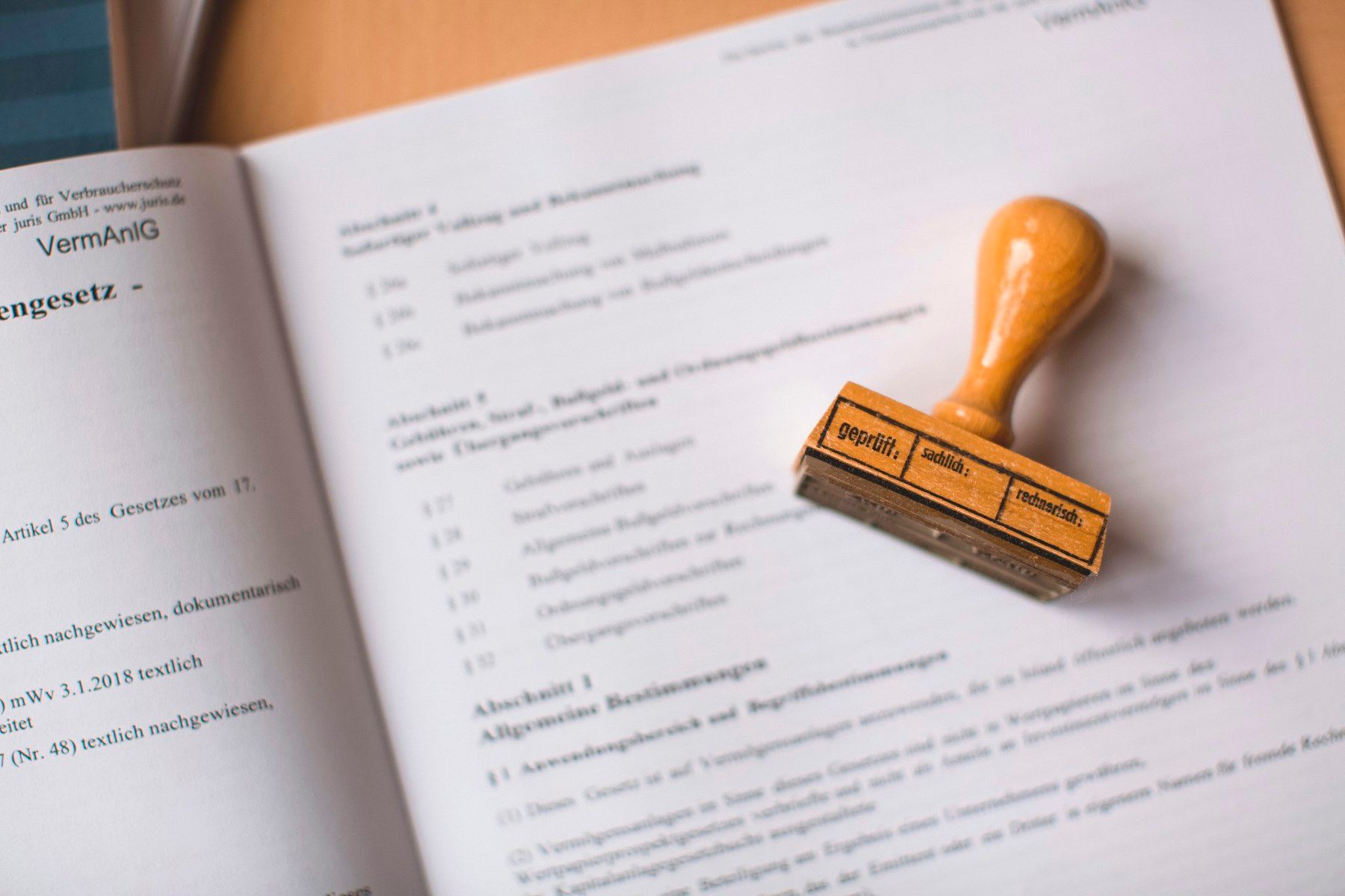 Stempel kayu diletakkan di atas halaman dokumen hukum yang terbuka